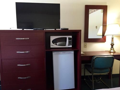 a microwave sitting on top of a dresser with a television at Colonial Inn in Brandon