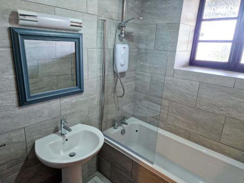 a bathroom with a sink and a shower with a mirror at Clyne Farm Centre in The Mumbles