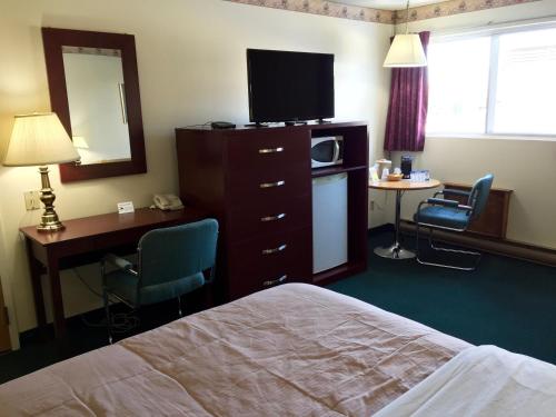 a hotel room with a bed and a desk and a television at Colonial Inn in Brandon