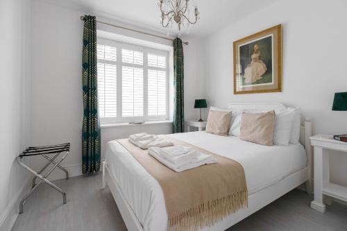a white bedroom with a large white bed with a chandelier at Stylish two bedroom apartment near Rookery Hall in Worleston