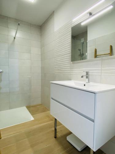 une salle de bain blanche avec un lavabo et un miroir dans l'établissement Le RAYNAL, à Rodez