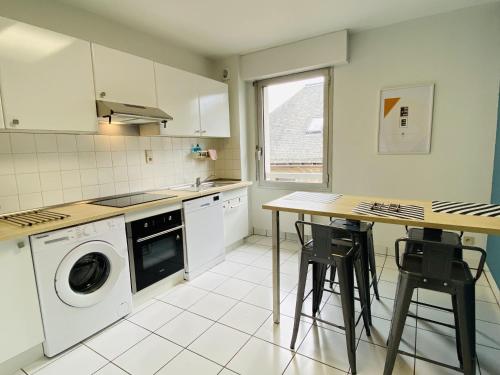 une cuisine avec une machine à laver et une table dans l'établissement Le RAYNAL, à Rodez