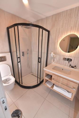 a bathroom with a shower and a toilet and a sink at Casalita Hotel in Kizkalesi