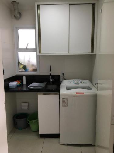 a kitchen with a white refrigerator and a window at Casa da bike Balneario Gaivota 150 mt do mar in Balneário Gaivotas