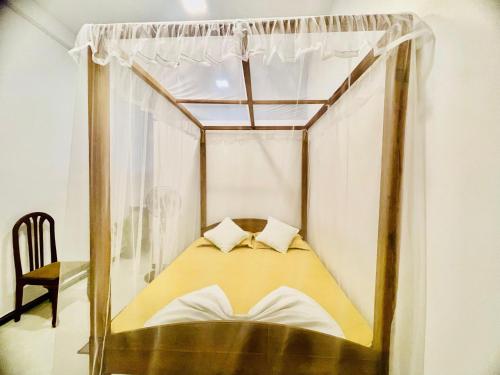 a canopy bed with two pillows in a room at Nimal's House in Dickwella