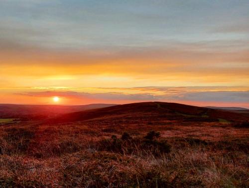 a sunset on top of a hill with the sun setting at Clyne Farm Centre in The Mumbles