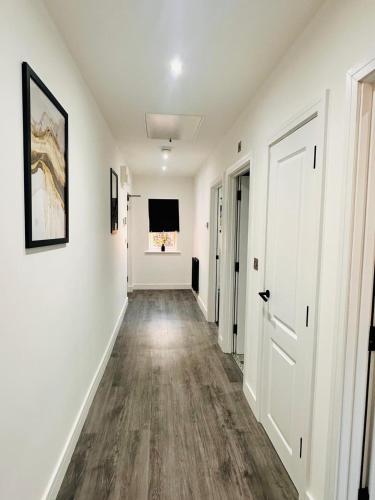an empty hallway with white walls and wood flooring at Under New Top Rated Management I Stylish 2BR Apartments I Central Hub I Free Parking I Work Ready Amenities in Peterborough