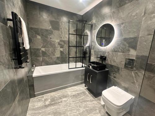 a bathroom with a tub and a toilet and a sink at Under New Top Rated Management I Stylish 2BR Apartments I Central Hub I Free Parking I Work Ready Amenities in Peterborough