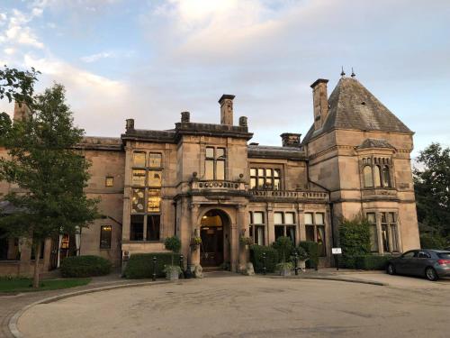 an old mansion with a car parked in front of it at Stylish two bedroom apartment near Rookery Hall in Worleston