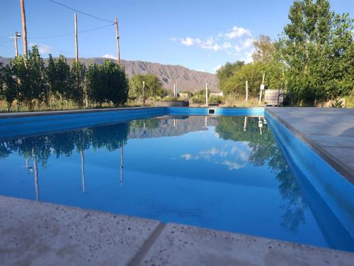 a pool of blue water with mountains in the background at Sol y Sombra - Cabaña - Zonda - San Juan in Zonda
