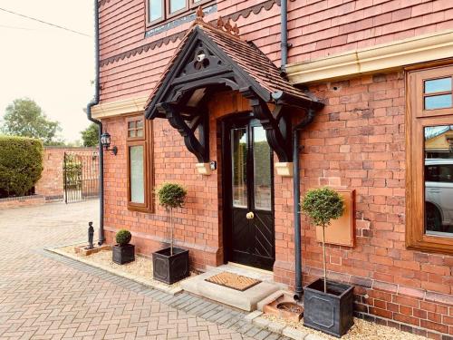 a brick building with a black door on it at Stylish two bedroom apartment near Rookery Hall in Worleston