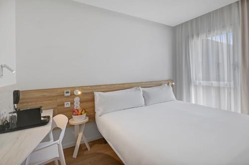 une chambre avec un grand lit blanc et un bureau dans l'établissement B&B HOTEL Leiria Fatima, à Leiria