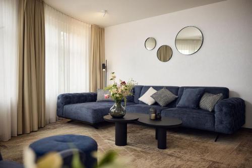 a living room with a blue couch and a table at Van der Valk Hotel Mechelen in Mechelen