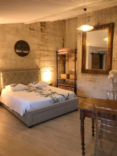 a bedroom with a bed and a table and a mirror at Le Joubert Hôtel Particulier in Uzès