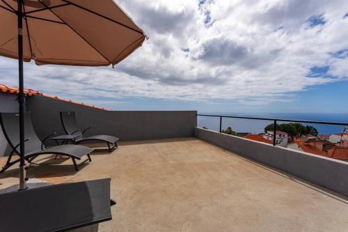 a patio with chairs and an umbrella on a balcony at Casa Do Sol in Arco da Calheta