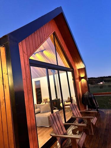 a small house with a deck with chairs and a couch at Cabanas Purunã in Balsa Nova