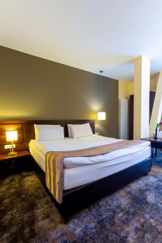 a large bed in a hotel room with two lamps at Golden Time Hotel in Braşov