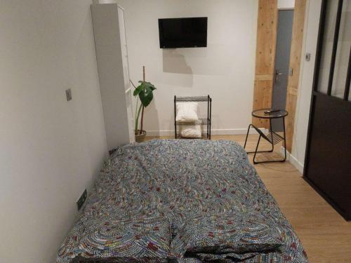 une chambre avec un lit avec une couverture dessus dans l'établissement Petit studio, à Millau