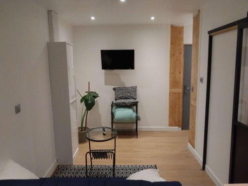Elle comprend un salon avec une chaise et une télévision murale. dans l'établissement Petit studio, à Millau