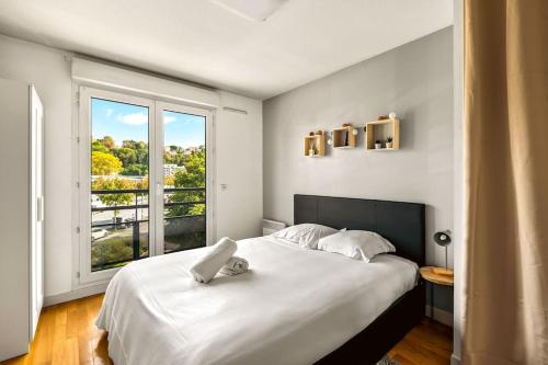une chambre avec un grand lit blanc avec une fenêtre dans l'établissement T2 paisible Vaise, avec parking métro direct Bellecour, à Lyon