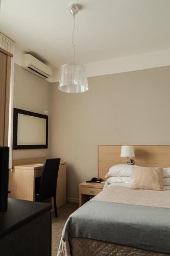 a bedroom with a bed and a desk and a lamp at Rouge Hotel International in Milano Marittima