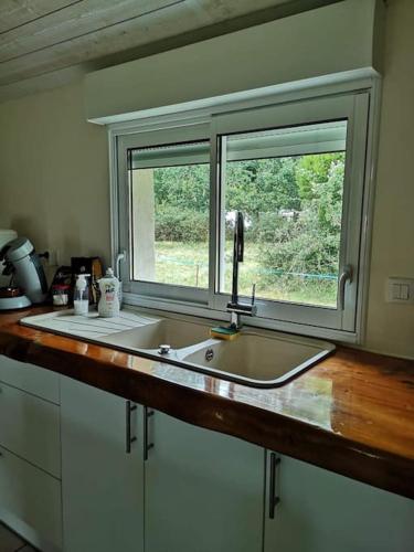 une cuisine avec un évier et une fenêtre dans l'établissement La maison vieille, à Hourtin