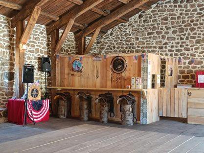 Cette chambre est dotée d'un mur en pierre avec une table et une scène. dans l'établissement GITE Le SALOON, à Mazan-lʼAbbaye