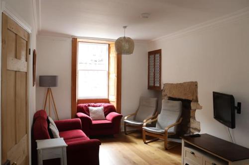 a living room with a red couch and two chairs at Historic 3 double bed whole house by castle in Lancaster