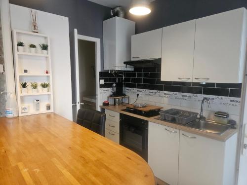 une cuisine avec des armoires blanches et une table en bois dans l'établissement Appart T2 avec cour, à Tours