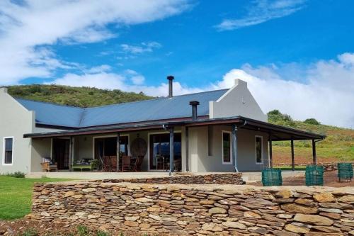 a white house with a stone wall at Ammara Farmstay in Bonnievale