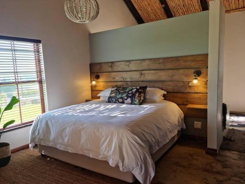 a bedroom with a large bed with a wooden headboard at Ammara Farmstay in Bonnievale