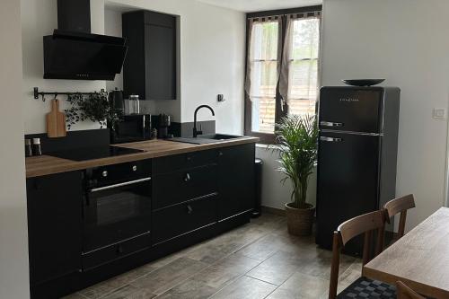 - une cuisine avec des armoires noires et un réfrigérateur noir dans l'établissement LaCartePostale, à Meusnes