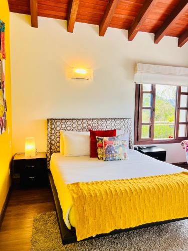 a bedroom with a large bed with a yellow blanket at Hotel Reserva Monarca in Salento