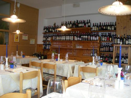 a restaurant with white tables and chairs and wine bottles at Altavilla Locanda E Tipica Trattoria in Bianzone