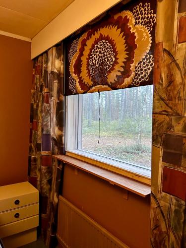 a window in a room with a sunflower curtain at Kaamos Old House in Autti