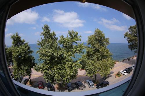 a view through a round window of trees and the ocean at Bayraktar Hotel in Akcakoca