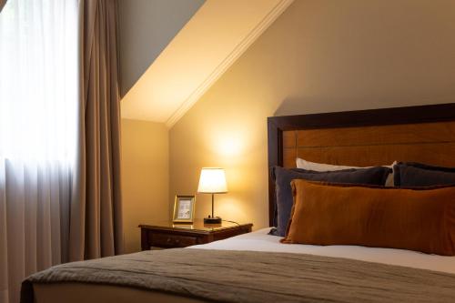 a bedroom with a bed and a lamp and a window at Hotel Puerta del Sur in Valdivia