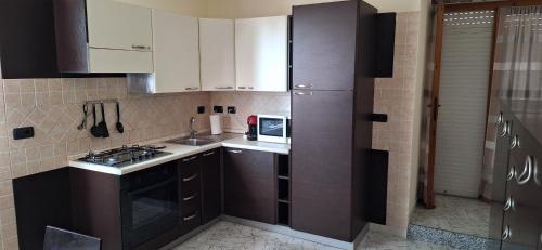 Una pequeña cocina con estufa y microondas. en Mara casa vacanza, en Maracalagonis