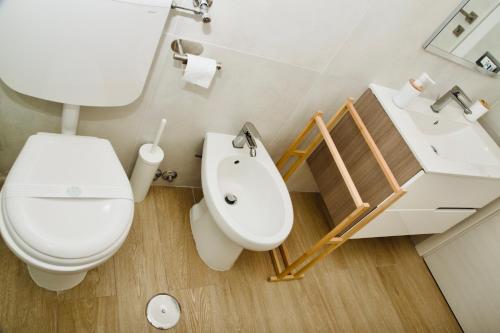 a white bathroom with a toilet and a sink at Casa Amare Aeroporto Fiumicino in Focene