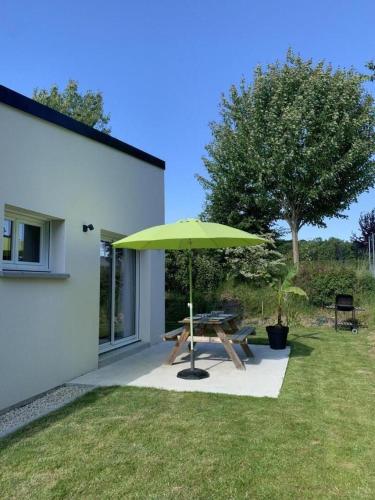 a picnic table with a green umbrella in a yard at Ker sandra in Saint-Germain-en-Coglès