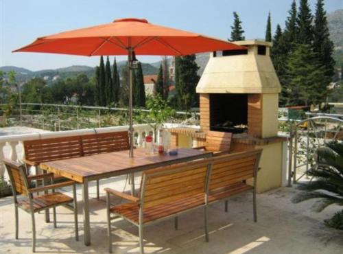 a table and chairs with an umbrella on a patio at Apartments Villa Novak in Slano