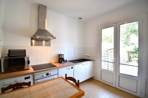 - une cuisine avec une table et un four micro-ondes dans l'établissement Laridente - Hossegor agréable villa située dans un quartier calme entre lac et océan, à Soorts-Hossegor