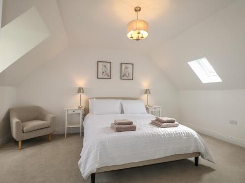 a white bedroom with a bed and a chair at Goodwood Retreat in Chichester