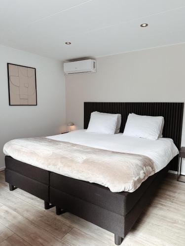 a bedroom with a large bed with white sheets at Vakantiehuisje Noé in Gorinchem