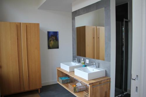 La salle de bains est pourvue de 2 lavabos et d'un miroir. dans l'établissement B&B Le Verger, à Bruxelles