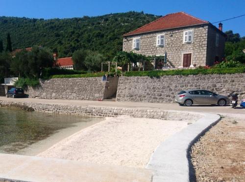 a house and a car parked next to a stone wall at Apartment Ana Broce in Broce