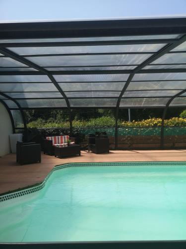 a swimming pool with awning and a patio with tables and chairs at Les Logis de l'Estuaire in Camoël