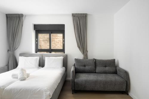 a bedroom with a couch and a chair at Adama by Sweett - Keren Hayesod Apartments in Jerusalem