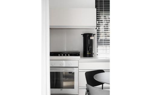 a white kitchen with a stove and a chair at Adama by Sweett - Keren Hayesod Apartments in Jerusalem