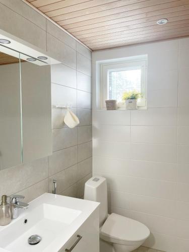 a bathroom with a sink and a toilet and a window at Sunny Beach Apartment Hiekkasärkät Kalajoki in Kalajoki